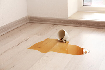 Wooden laminate floor with overturned cup of coffee