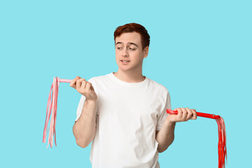 Confused young man with whips on blue background