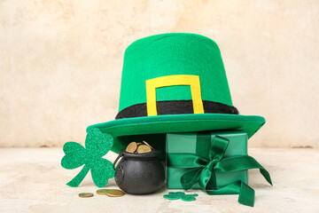 Pot with golden coins, gift box and leprechaun hat on light grunge background. St. Patrick's Day...