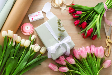 Obraz na płótnie Canvas Composition with gift box, packing materials and beautiful tulip flowers for International Women's Day on wooden background