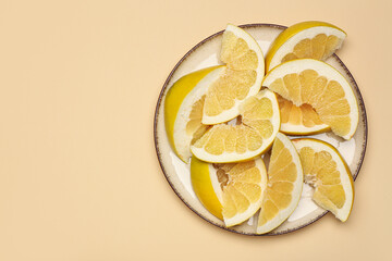 Plate with pomelo fruit slices on beige background