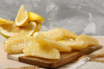Board with tasty pomelo pieces on grey grunge background