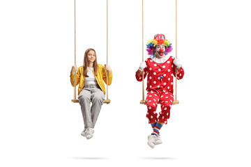 Teenage girl and a clown swinging on swings