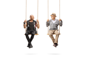 Punk and a senior man sitting on swings and looking at each other