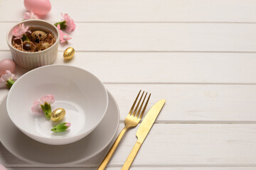 Modern Easter decorated table setting with flowers and eggs on white wooden background