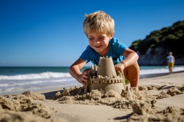 Blond boy in a blue T-shirt making a castle on the beach on a sunny summer day