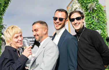 Newlywed gay male couple poses with friends for a memorial photo while laughing