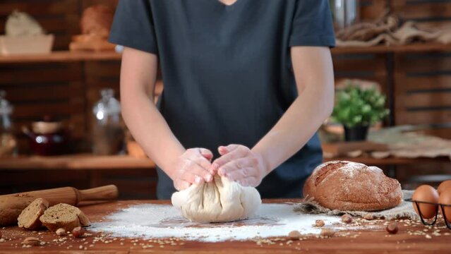 Traditional baking of bread in rural style, woman kneading dough in kitchen, closeup hands on table