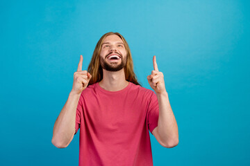 Portrait of positive young man look direct fingers up empty space proposition isolated on blue...