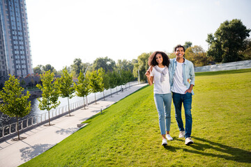 Full body portrait of cheerful peaceful soulmates hold arms cuddle walk green grass city center outside