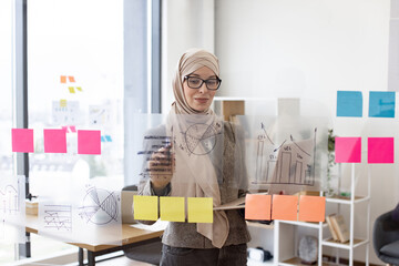 Female administrative manager preparing for presentation at work. Arabian woman in hijab holding...