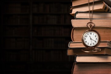 Old clock on a chain on old books in library