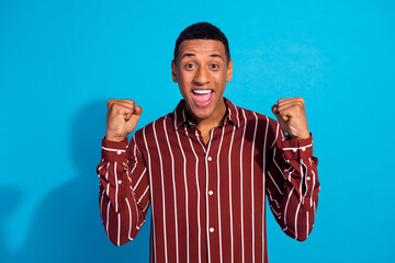 Photo portrait of attractive young man raise fists celebrate win lottery dressed stylish striped...