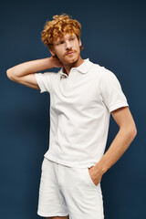 wealthy redhead man in white attire with hand in pocket looking away on blue, timeless fashion