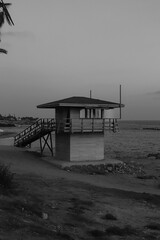 Wooden lifeguard safety tower station along the boardwalk beach of Paphos, Cyprus in black and white