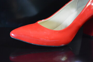 Casual shoes, women's red pump shoes with wide heels made of genuine patent leather located on a black glossy background.