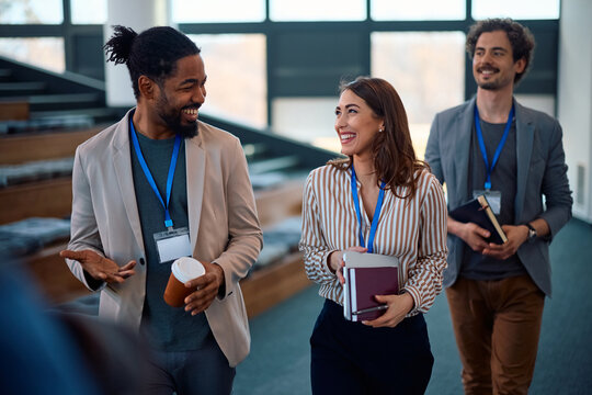 Happy colleagues talking while leaving conference room after business seminar.