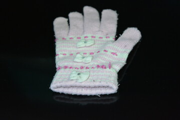 Clothing, women's wool pink white glove with bows arranged on a black glossy background.