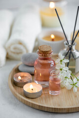 Fototapeta na wymiar Aromatherapy, home decor concept. Glass perfume bottle, elegant composition with spring flowers. Burning candles, spa setting, essential oils, organic pure aromatic ingredients, atmosphere of relax