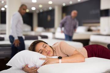 Charming woman sleeping on a new mattress in a furniture store
