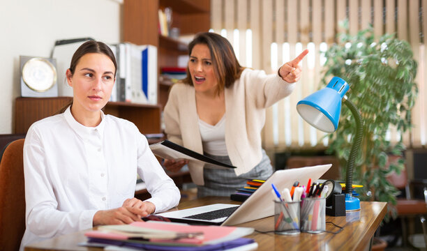 Outraged business woman expressing dissatisfaction with work of confused secretary in office