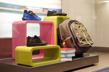 Shoes and backpack on a store window, teenage clothes, preparing for school. Soft focus.