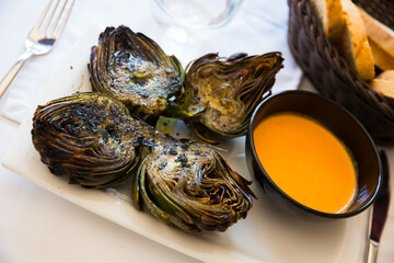 Plate of tasty Catalonian dish - grilled artichokes with romesco sauce