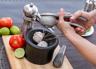 Squeezing the lemons over the mortar for the preparation of the sauce that also contains garlic, cumin, tomatoes and pepper