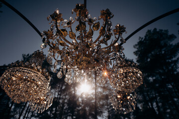 Luxurious crystal chandeliers in the middle of a pine forest in the glow of the sunset. Fabulous...