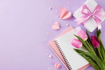 Gifts of appreciation: thoughtful gestures for her. Top view of pink tulips, heart-shaped paper cutout, notebooks, gift box with pink ribbon on lavender background with space for heartfelt messages