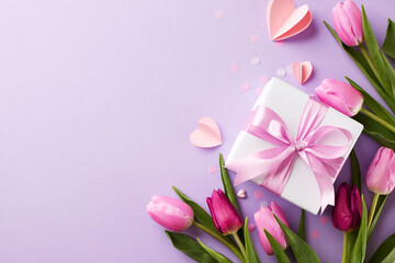 Elegance in gifting: delighting the special women in our lives. Top view shot of tulips, gift box, scattered paper hearts on lavender background with space for expressions of love or marketing slogan