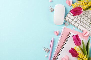 Сelebrating Women's Day: touches of spring at the workspace. Top view shot of notebook, keyboard, computer mouse, heart cutouts, pen, pink tulips on light blue background with space for greetings