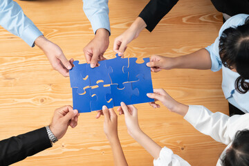 Top view multiethnic business people holding jigsaw pieces and merge them together as effective...