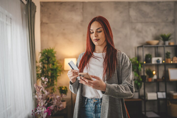 young woman caucasian female hold credit card online shopping at home