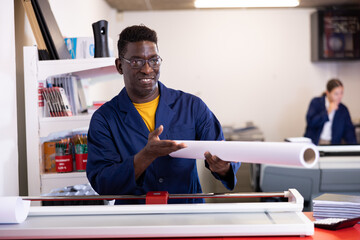 Happy middle-aged African American man in a blue robe uniform holding whatman in a roll in the...