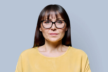Headshot portrait of serious mature woman on grey background