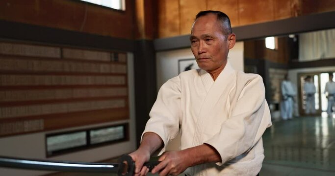 Aikido, sword and master fight with a katana in traditional Japanese class, gym or competition. Martial arts, sensei and mature fighter training with weapon for sport, practice and challenge