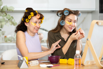 Adult and young women curl their hair with curlers and use hydrogel eye patches