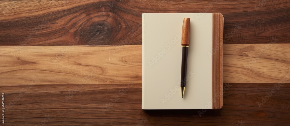 Poster a pen rests on top of a closed notebook on a wooden table, creating a simple yet functional workspac