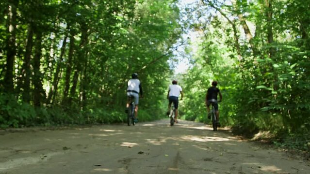 Three Boys Start Riding Bicycles on a Gravel Road in Forest