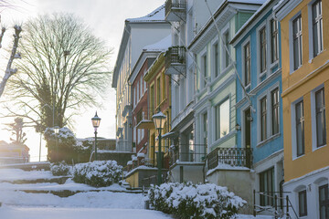 Typical houses in Bergen at winter, cold winter day on the streets of Bergen, snow covered roads and tall colorful houses.