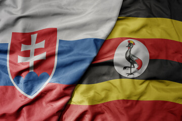 big waving national colorful flag of uganda and national flag of slovakia .