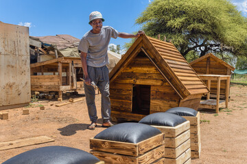 african american carpenter worker at his workplace , he is doing wendy houses , dog houses, on the side of the road, street vendor with a small business