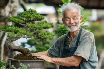 Fotobehang Senior man carefully holding a bonsai tree in a pot. © Joaquin Corbalan