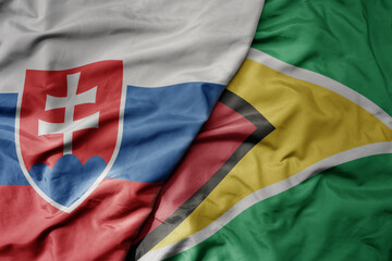 big waving national colorful flag of guyana and national flag of slovakia .