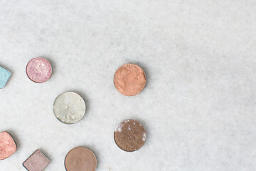 Overhead view of expired eyeshadow, moldy eyeshadows on a marble table