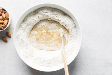 making almond biscotti dough in a white bowl, process of making almond cantucci cookie dough in...