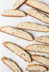 almond biscotti on white parchment lined tray, almond cantucci cookies on a white chopping board,...