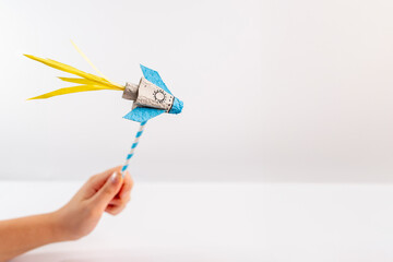 a close up of a person holding a paper rocket, with a white background, © Elena