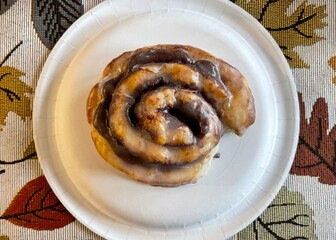 Cinnamon roll on white paper plate 